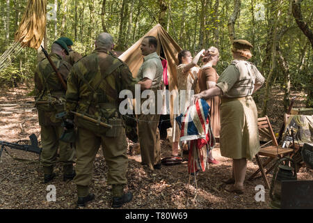 Woodhall Spa 1940s world war two festival re-enactment weekend, civilians and military personnel within a shaded woodland clearing. Stock Photo