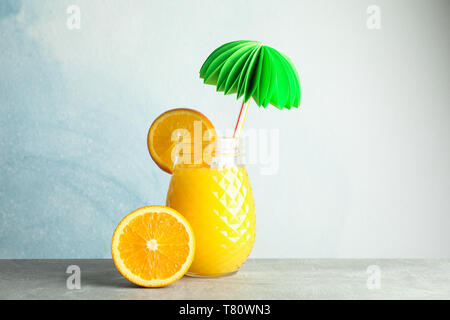 Glass jar with fresh orange juice, decorative palm and oranges on grey table against color background, space for text. Fresh natural drink Stock Photo