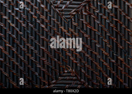 Natural texture of braided wicker of dark color. Horizontal and vertical lines. Ocher, brown and black tones. Stock Photo