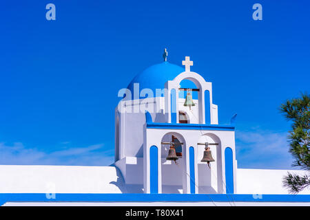 Blue dome and bell tower of a whitewashed Greek church on the hill near Oia, Santorini, Greece Stock Photo