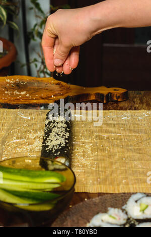 Women's hands close-up in a restaurant sprinkle sesame oil during the preparation of sushi 2019 Stock Photo