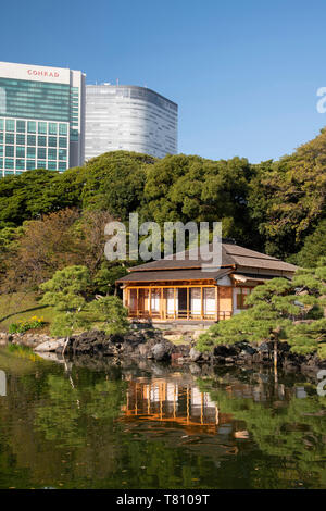 A modern highrise hotel above the Tsubame-no-ochaya, a tea house on a lake in the Hama-rikyu Gardens, Tokyo, Honshu, Japan, Asia Stock Photo