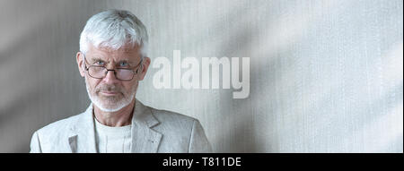 portrait of a gray-haired man in light clothes and glasses Stock Photo