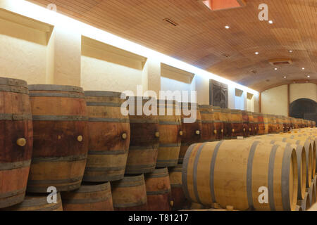 Wine cellar with rows of wooden barrels containing aging alcoholic drink . Stock Photo