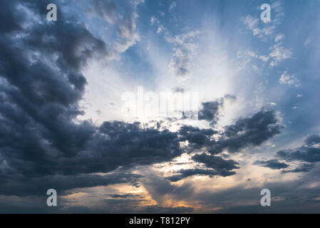 Sunset behind dark grey clouds on sky Stock Photo