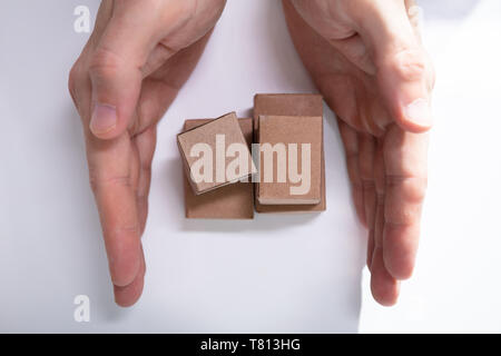 Close-up Of Hand Holding Stack Of Miniature Movable Cardboard Boxes On Desk Stock Photo