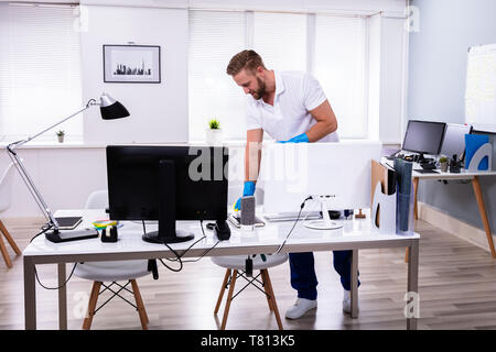 Janitor cleaning white desk in modern office Stock Photo