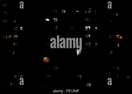 2019, May - Sao Paulo, Brazil. Multiple windows of an apartment building at night. Some yellow, some blue, some light on, some light off. Stock Photo