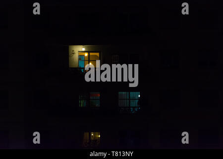 2019, May - Sao Paulo, Brazil. Multiple windows of an apartment building at night. Some yellow, some blue, some light on, some light off. Stock Photo