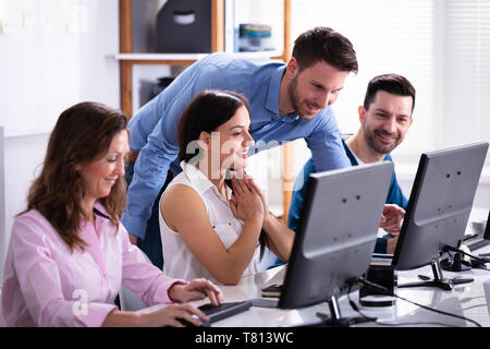 Group Of Happy Business People Using Laptop Discussing At Workplace In Office Stock Photo