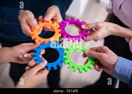 Close-up Of Businesspeople Connecting Colorful Gears In Office Stock Photo
