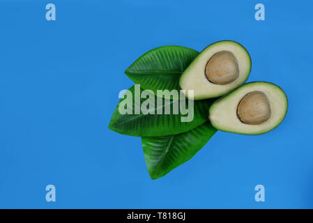 ripe fruit green avocado and a half on a blue background Stock Photo