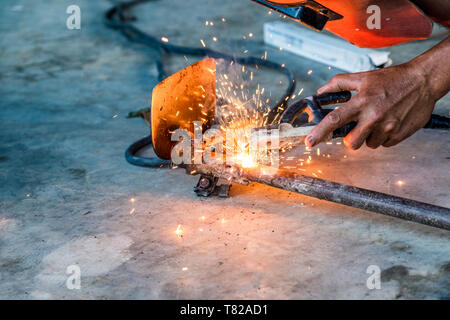 Industrial worker using welder machine is welding a spade tool with sparking Stock Photo
