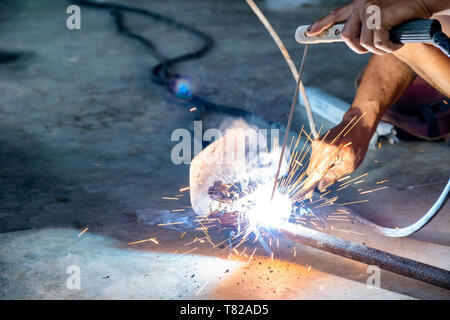 Industrial worker using welder machine is welding a spade tool with sparking Stock Photo
