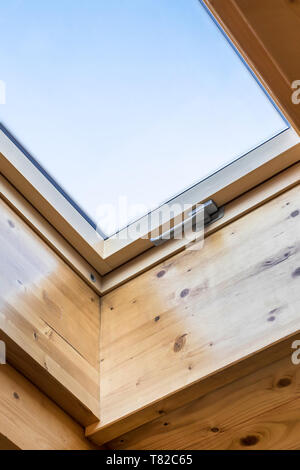Skylight window in wooden house attic. Room with slanted ceiling made of natural eco materials. Environment friendly house. Stock Photo