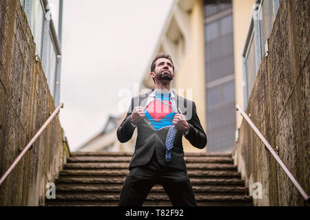 Young businessman acting like a super hero and tearing his shirt Stock Photo