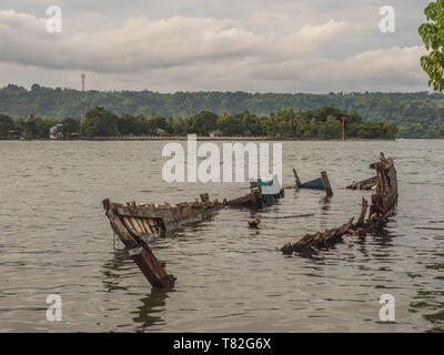 Wreck of wooden boat laying on the coast of the island of Ambon in Indonesia. Ambon Island, Central Maluku, Indonesia Stock Photo