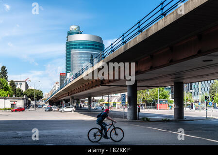 Madrid, Spain - May 1, 2019: Cyclist running under flyover in Paseo de la Castellana avenue against modern skyscrapers in  Financial District Stock Photo