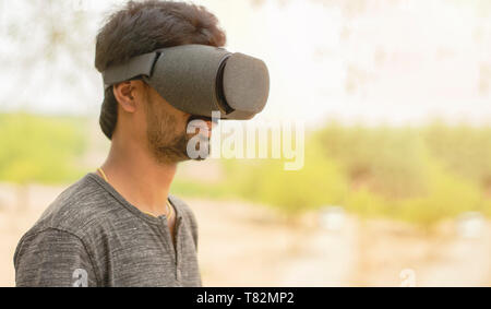 Young man using a VR headset glasses outside. Stock Photo