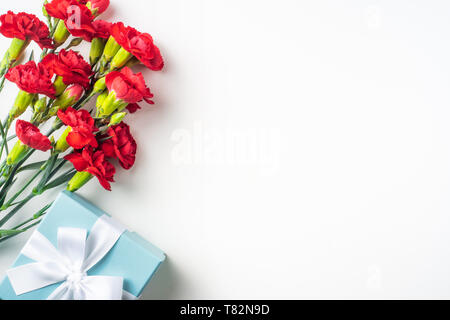 event design concept - top view of a bunch of red carnation and gift box isolated on white background for mothers , fathers day and valentines day, we Stock Photo