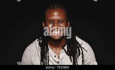 Happy african male with long dreadlocks isolated on black background. Portrait of smiling man looking at camera. Stock Photo
