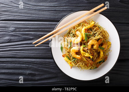 Singapore Noodles Mei Fun with shrimps, sausage, omelet and vegetables close-up on a plate on the table. horizontal top view from above Stock Photo
