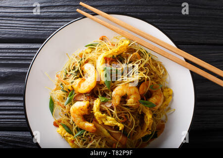 Fried Chinese rice noodles with sausage, shrimps and vegetables close-up on a plate on the table. Horizontal top view from above Stock Photo