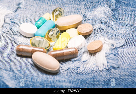 Health care and illness. Dose and addiction. Drug addiction. Medicine and treatment concept. Drugs on denim background. Set of colorful pills. Mixing medicines. Fast treatment. Medicine prescription. Stock Photo