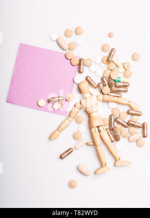 Health and treatment. Health care and problems. Immunity and medicine vitamins. Overdose and death. Medicine prescription. Wooden human dummy lay on pile of pills and tablets. Take medicine concept. Stock Photo