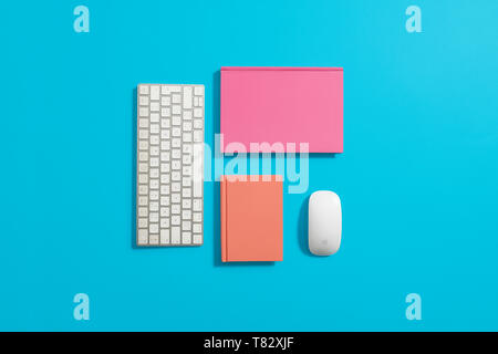 Orange hardcover notebook, diary, journal on a blue background with computer equipment around it Stock Photo