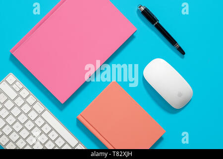 Orange hardcover notebook, diary, journal on a blue background with computer equipment around it Stock Photo