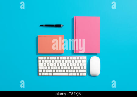 Orange hardcover notebook, diary, journal on a blue background with computer equipment around it Stock Photo