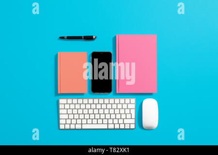 Orange hardcover notebook, diary, journal on a blue background with computer equipment around it Stock Photo