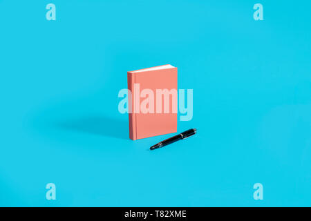 Orange notebook, diary, journal on a blue background with a black pen with copy space and room for text Stock Photo