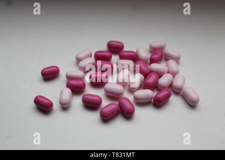 smooth bright pink candy drops look like medicine pills lay on table Stock Photo
