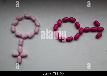 smooth bright pink candy drops look like medicine pills lay in symbol male and female   on table Stock Photo
