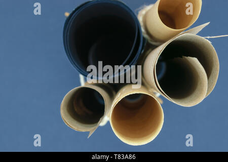 Side view of bunch of various beige and black craft scroll papers tied up with beige rope on blue background Stock Photo