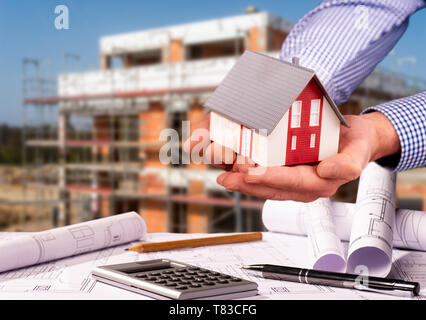 Construction plans with calculator, architectural model and a shell in the background Stock Photo