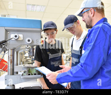 trainer and apprentice in technical vocational training at a drilling machine Stock Photo