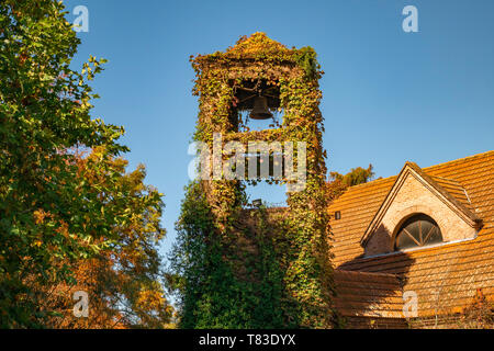 Yellows, reds and ochres in a bell tower in a sunny autumn park. The colors and luminosity of autumn take over this rural image in the suburbs. Stock Photo