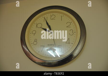 A large round clock hangs on the wall Stock Photo