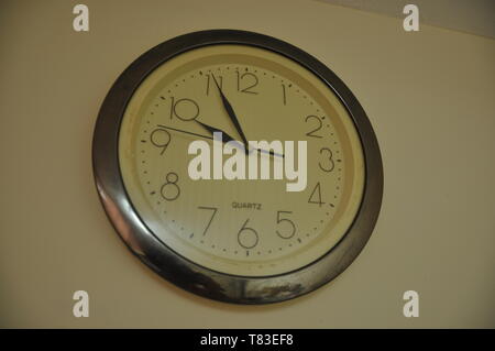 A large round clock hangs on the wall Stock Photo