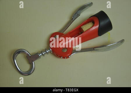 A red and silver bottle opener on the table Stock Photo