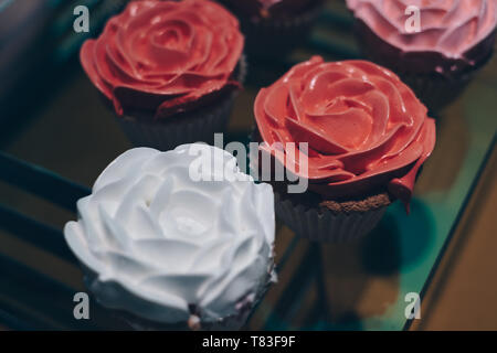 Cupcakes with peach, white, and pink rose design icing. Selective focus. Copy space. Stock Photo