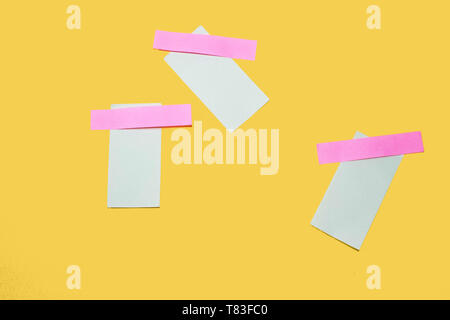 Blank sticky notes posted on a yellow background with a pink tape Stock Photo