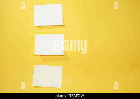 Three blank yellow sticky notes arranged vertically on an orange background Stock Photo