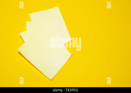 Three blank yellow sticky notes isolated on an orange background Stock Photo