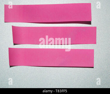 Pink small elongated sticky notes. Three blank pink sticky notes on a silver background. Stock Photo