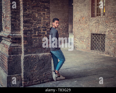 Attractive young man standing against old brick wall Stock Photo