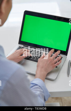 Over The Shoulder View Of Businesswoman Using Green Screen Laptop In Office Stock Photo